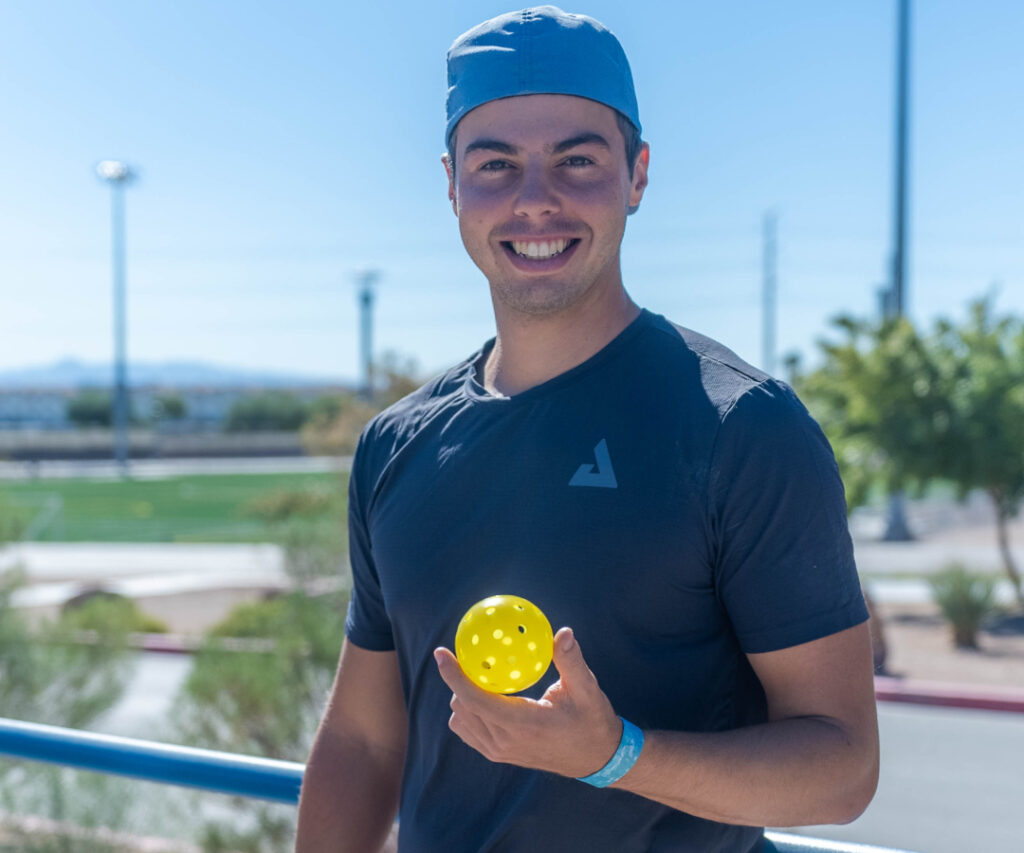 ben johns holding a yellow heleus ball smiling in front of the camera